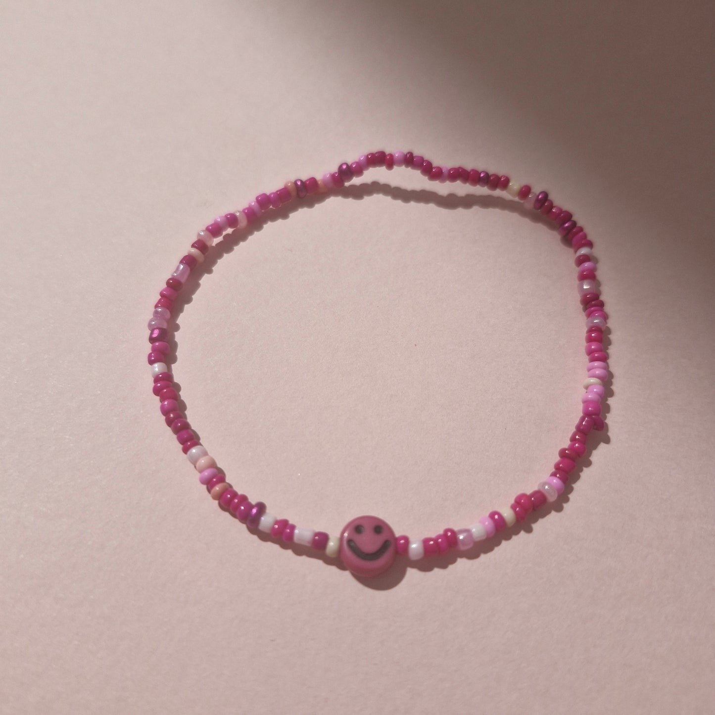 Pink Friendship Bracelet With A Bright Pink Smiley Face