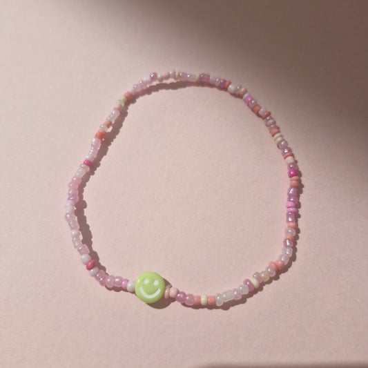 Light Pink Friendship Bracelet With A Green Smiley Face