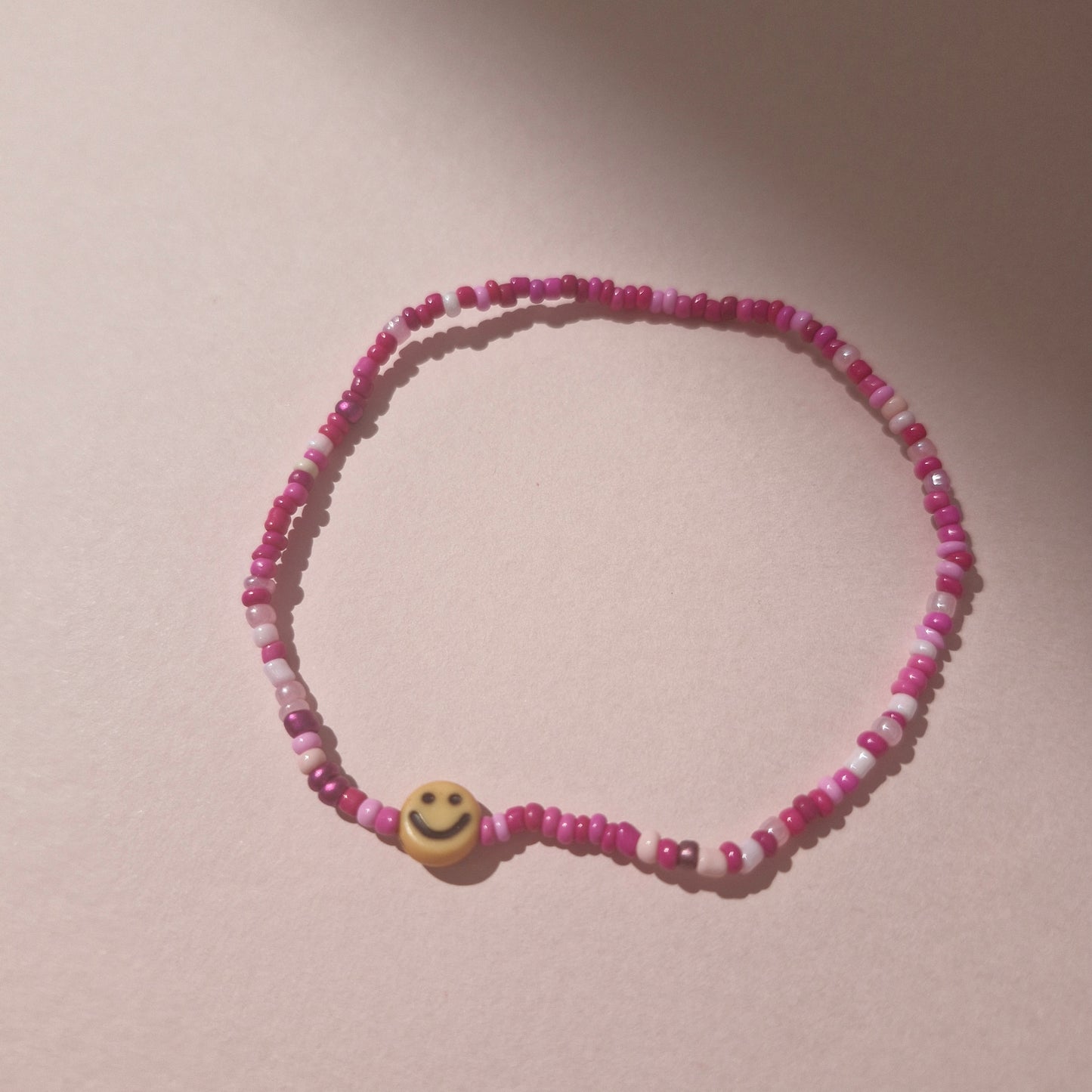 Pink Friendship Bracelet With A Orange/Yellow Smiley Face