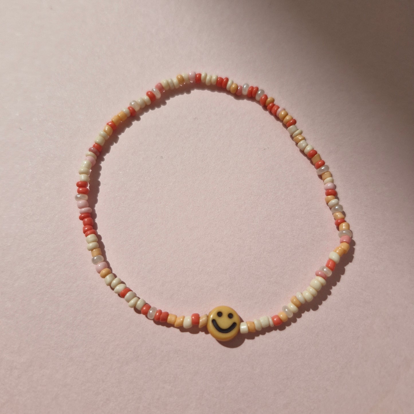 Coral/Peach Friendship Bracelet With An Orange Smiley Face