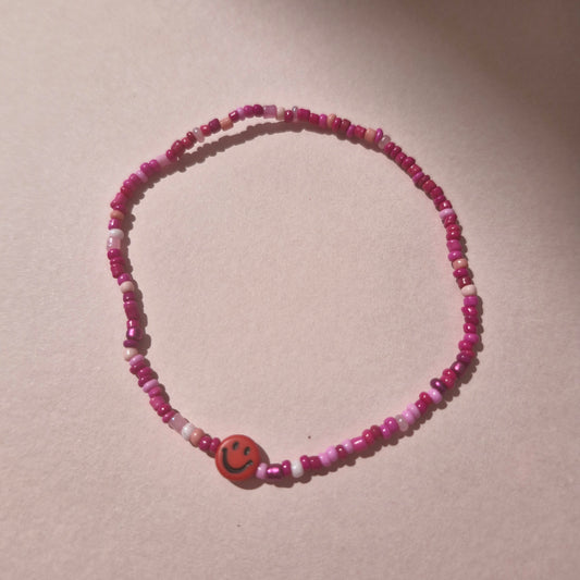 Pink Friendship Bracelet With A Bright Red Smiley Face