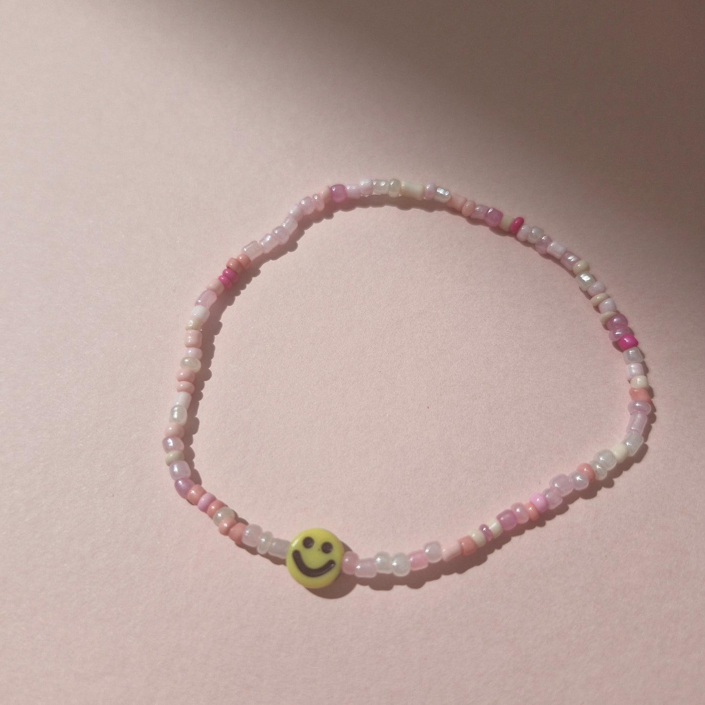 Light Pink Friendship Bracelet With A Yellow Smiley Face