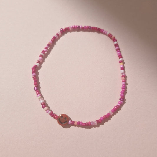 Pink Friendship Bracelet With A Dark Red Smiley Face