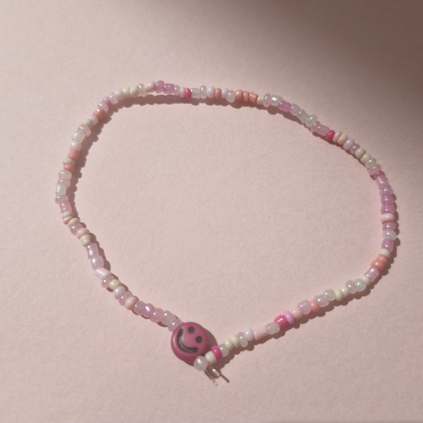 Light Pink Friendship Bracelet With A Bright Pink Smiley Face