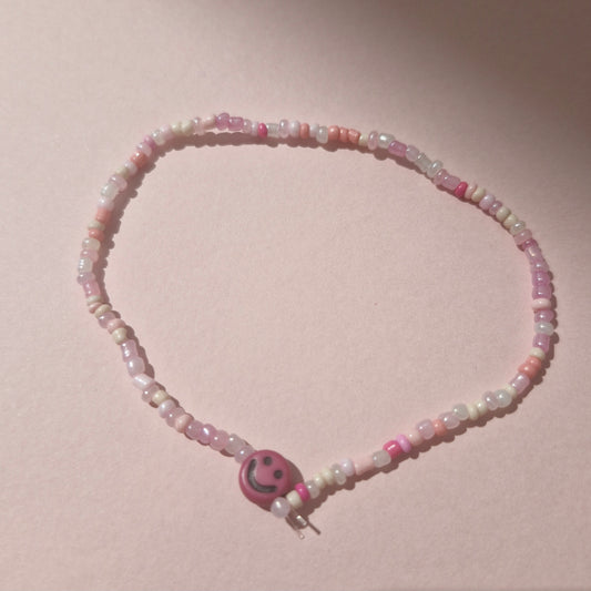 Light Pink Friendship Bracelet With A Bright Pink Smiley Face