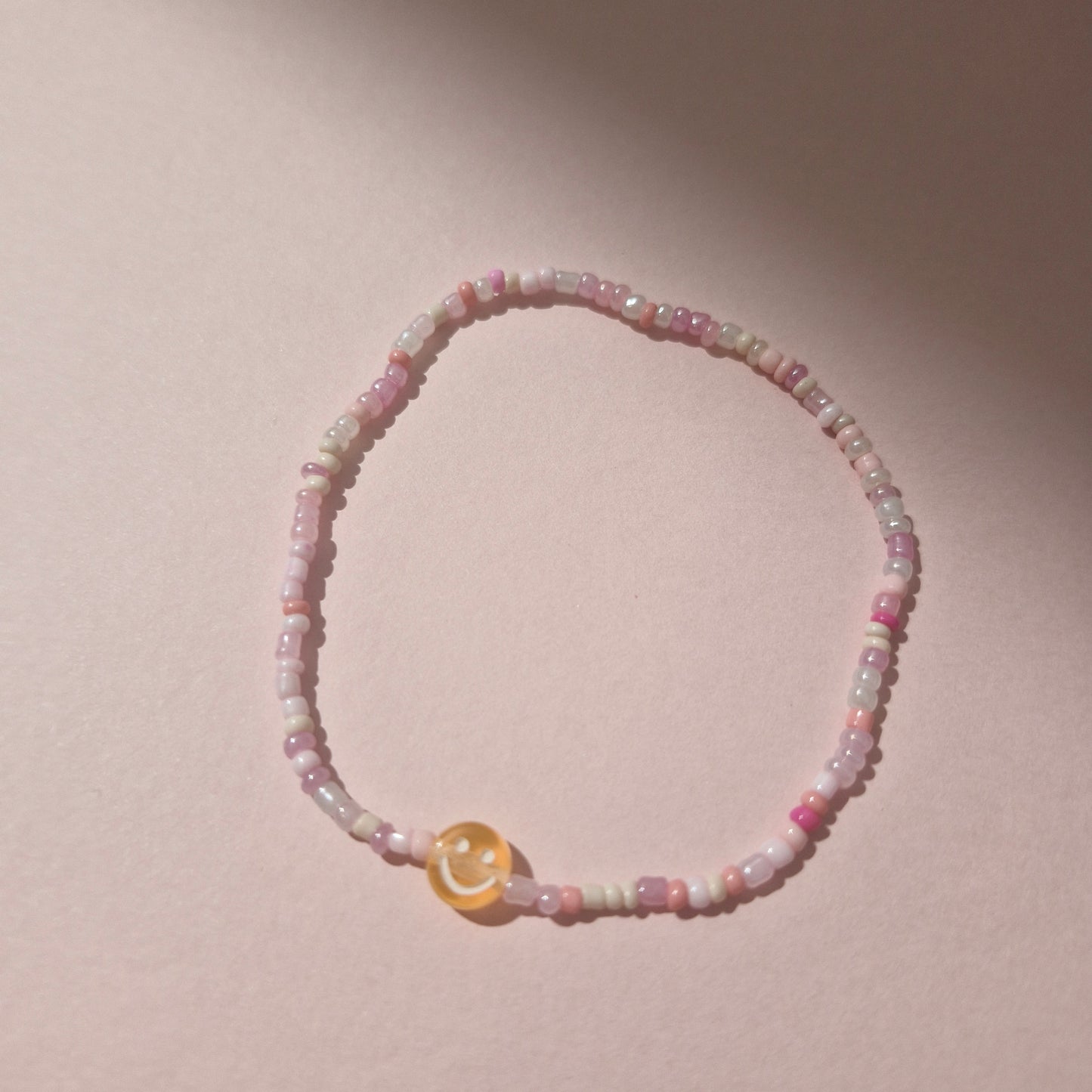 Light Pink Friendship Bracelet With An Orange Smiley Face