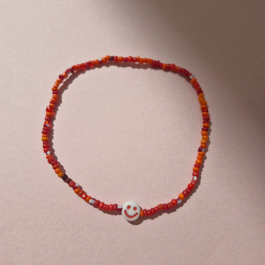 Red Friendship Bracelet With A Red Smiley Face