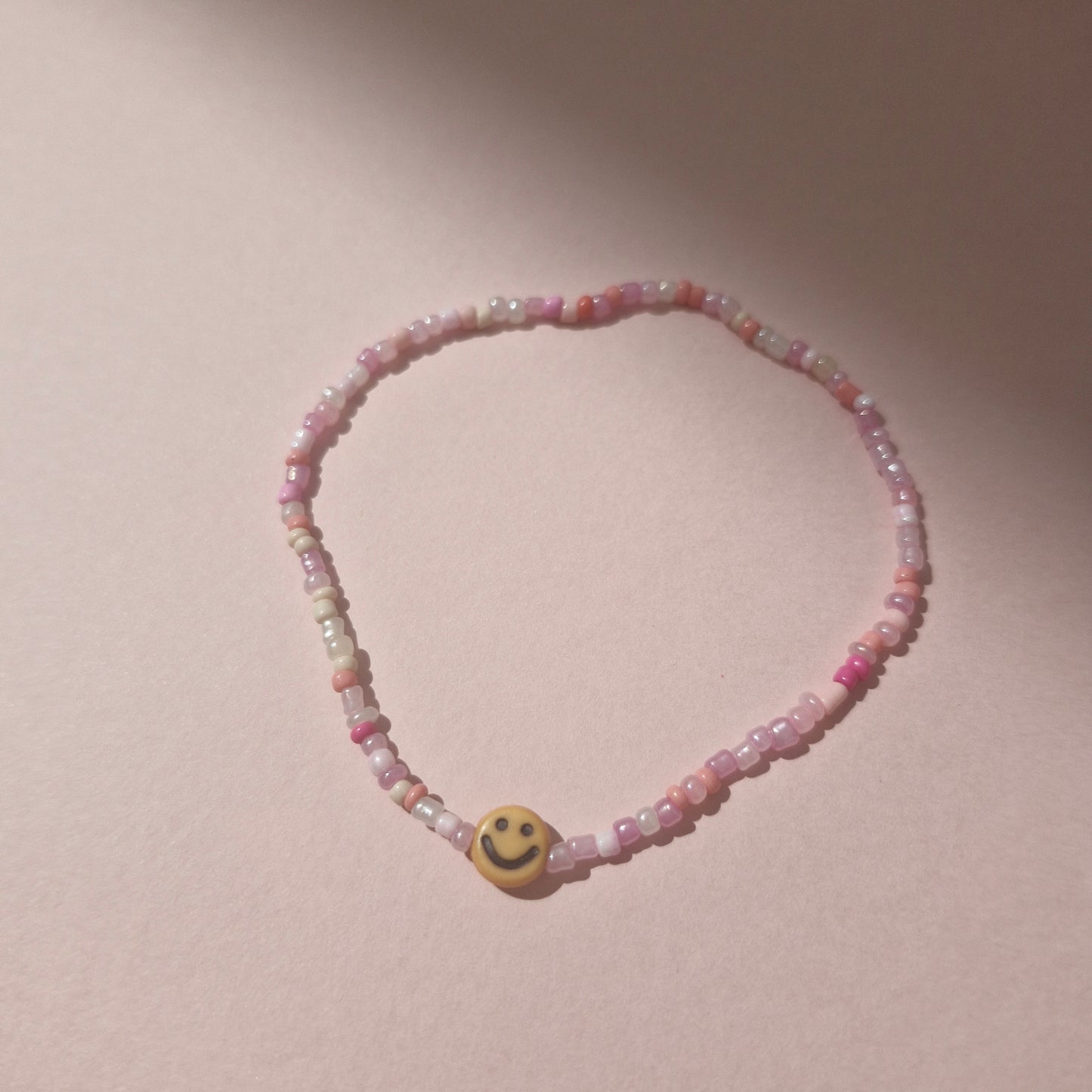 Light Pink Friendship Bracelet With An Orange Smiley Face