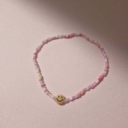 Light Pink Friendship Bracelet With An Orange Smiley Face